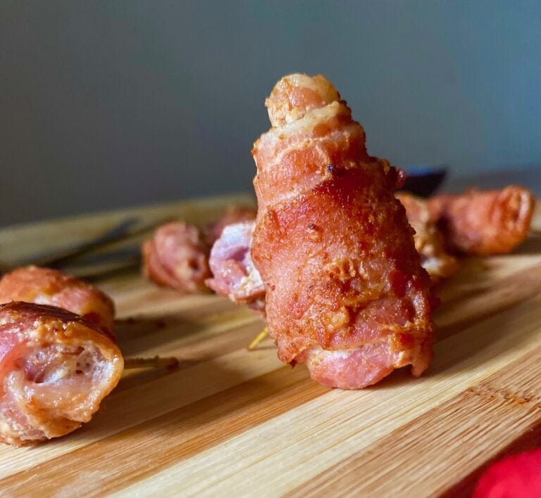 Yummy bacon rolls on a wooden plate.