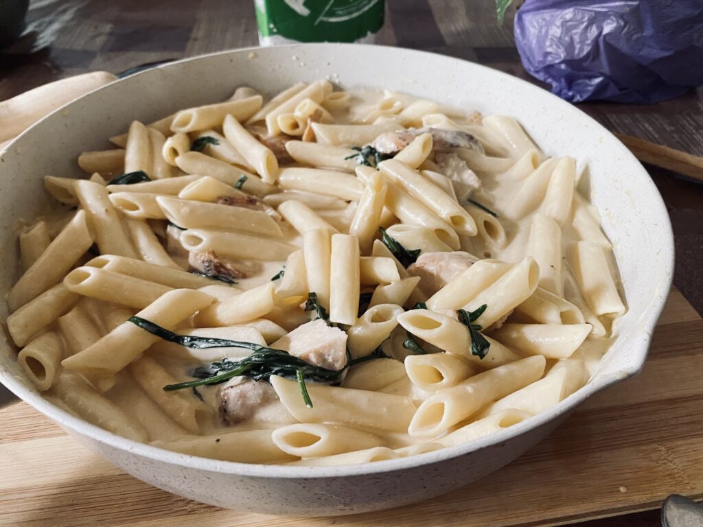 Creamy Chicken Penne: Penne pasta in a creamy sauce with tender chicken pieces and fresh herbs, served in a white pan, showcasing a delicious homemade pasta dish.