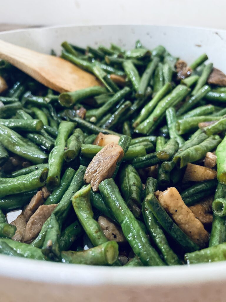 String beans with pork cooked in a white pan.