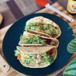 Three wrap tortillas with scrambled egg and lettuce on a plate.