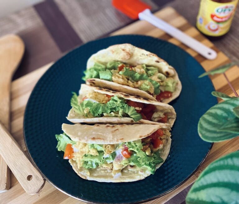 Three wrap tortillas with scrambled egg and lettuce on a plate.