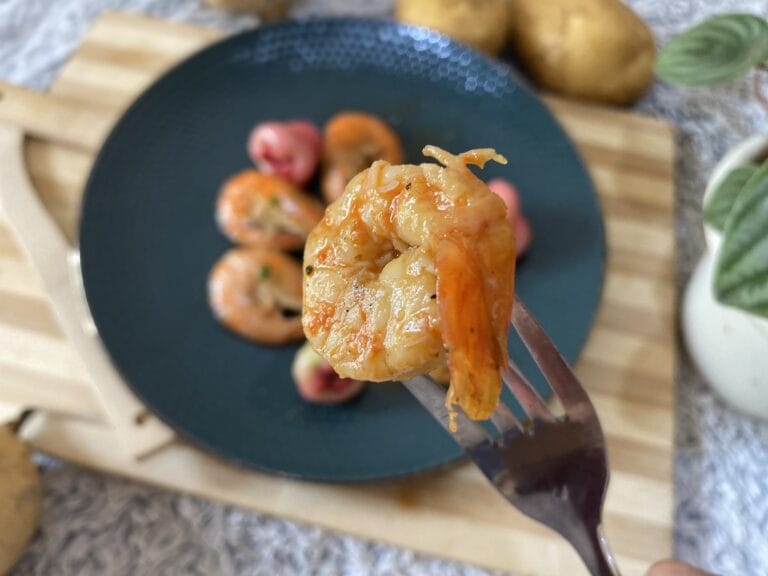 Shrimp on a fork. and many more shrimp on a plate.